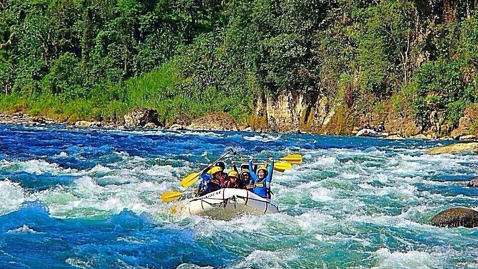 A group of people kayaking on a river surrounded by dense forest.
