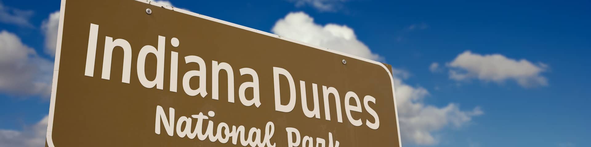 Indiana Dunes National Park (Indiana) Road Sign Against Blue Sky and Clouds.