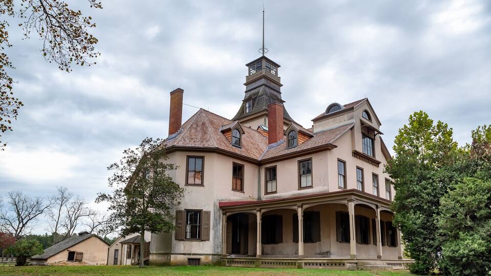 A large, historic house with a prominent tower and a covered porch.