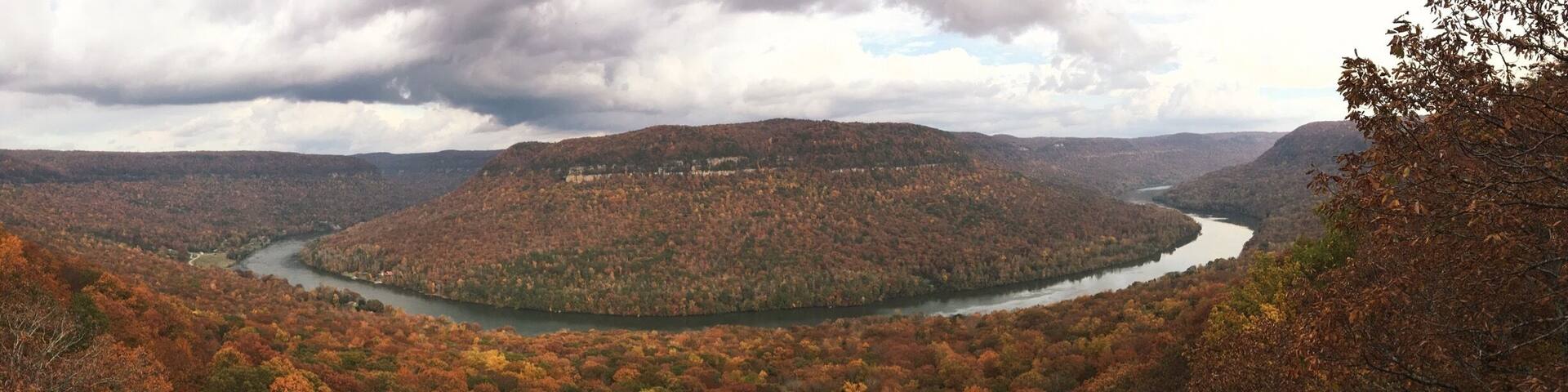 A river winding through a forested valley with autumn foliage.