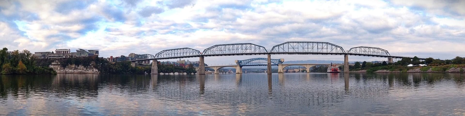 A bridge over a river with a cityscape in the background.