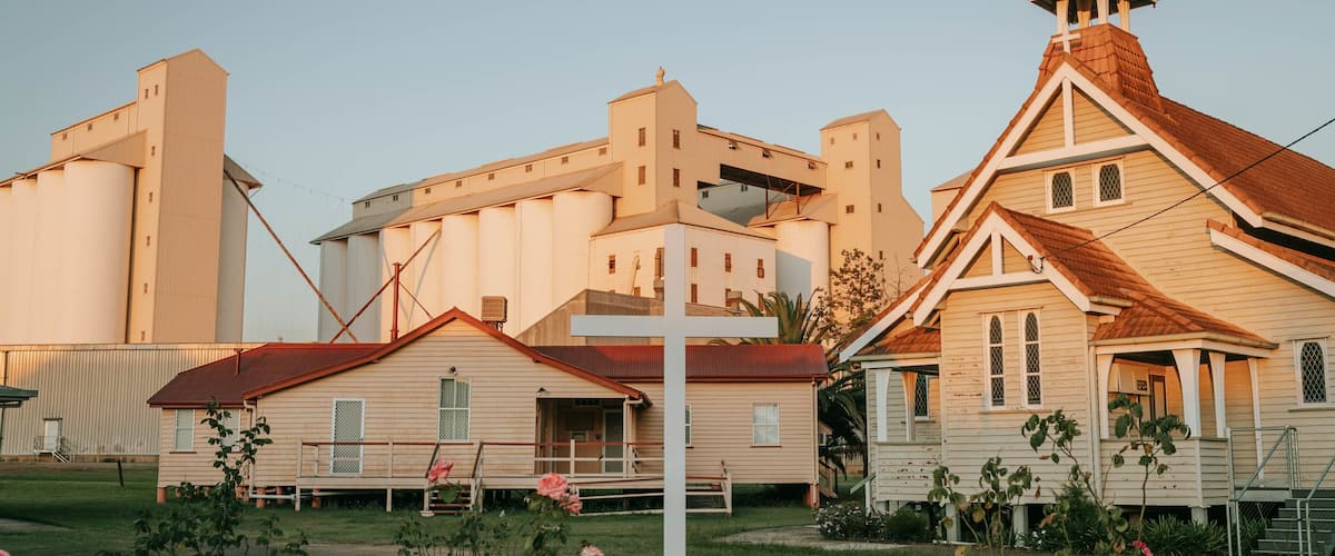 A rural landscape with a church, a grain silo, and residential buildings.