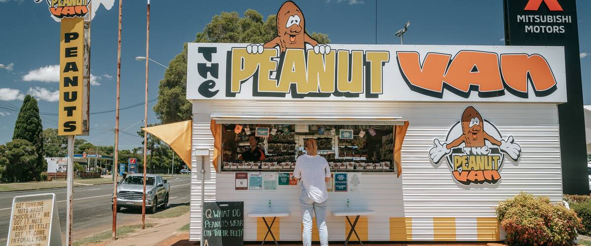 A roadside snack stand named "The Peanut Van" with a cartoon peanut character logo.