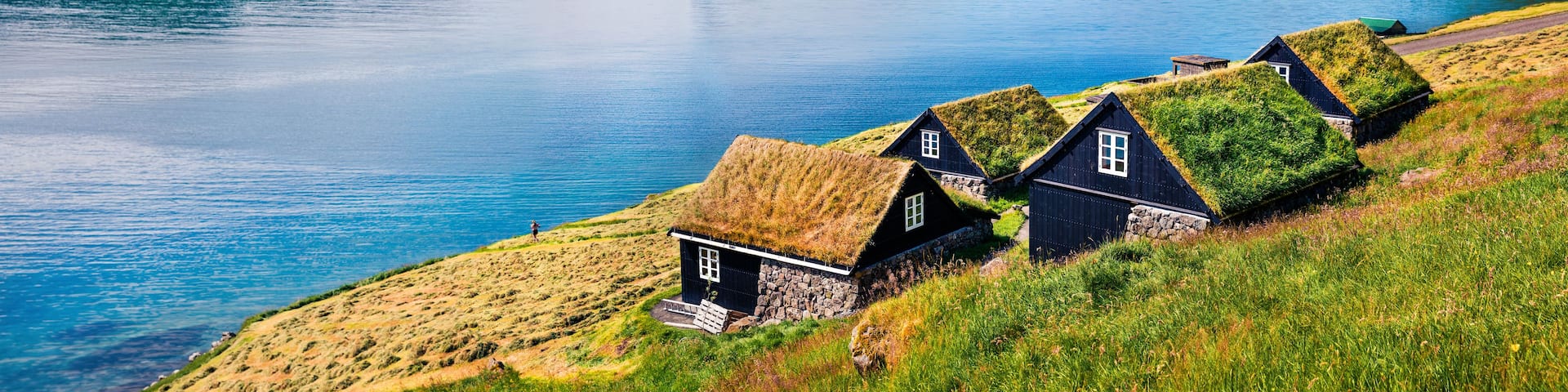 A coastal village with traditional houses, a fjord, and a prominent cliff.