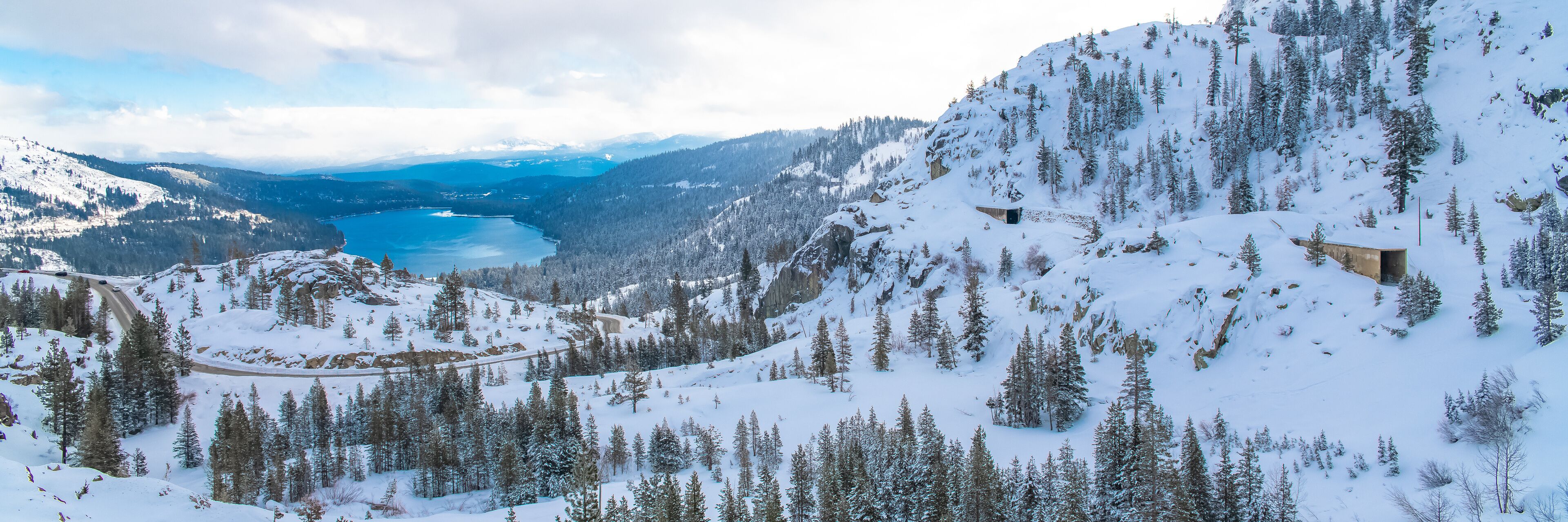 The Donner lake under the snow in winter, in California, panorama, with tunnels in the mountain for the train
