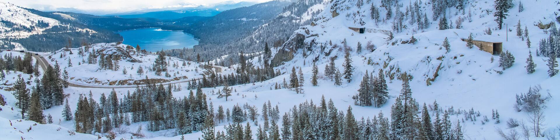 The Donner lake under the snow in winter, in California, panorama, with tunnels in the mountain for the train