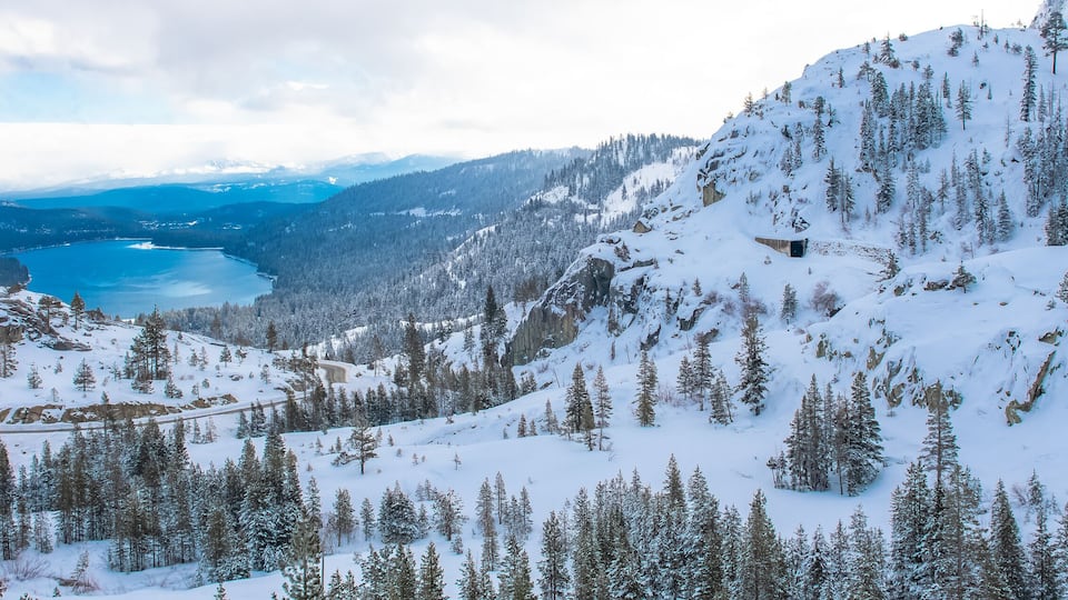 The Donner lake under the snow in winter, in California, panorama, with tunnels in the mountain for the train
