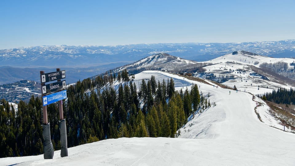 Trail sign at Park City Ski Area, Utah. Top view to the valley with mountains range during early spring weather conditions.