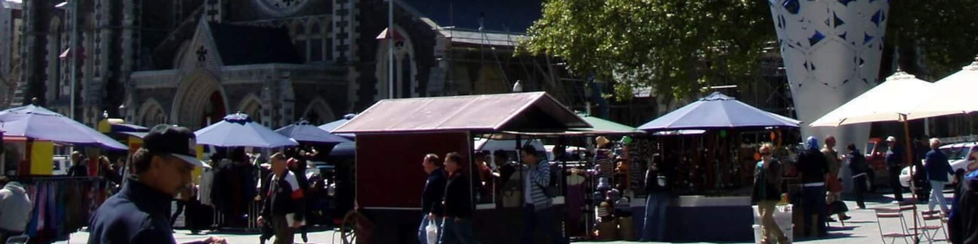 A historic church with a tall spire and a large decorative metal sculpture in a public square.