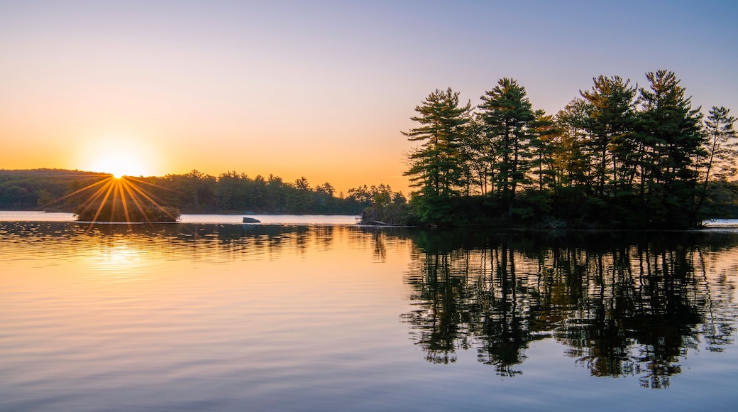 Peaceful sunrise over the lake at Harriman park, featuring sun raising over the mountains on the background