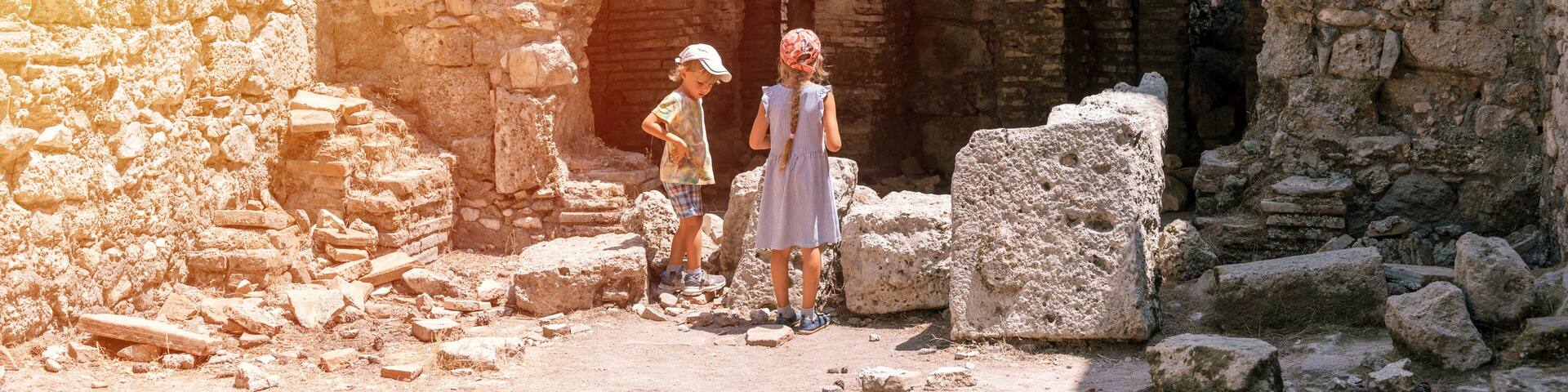 kids sibling girl and boy travelers travel and explore the ancient excavations of the ruins of the ancient Lycian city of Phaselis in Turkey in summer holidays in nature mountains outdoor. banner