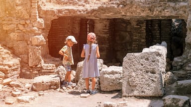 kids sibling girl and boy travelers travel and explore the ancient excavations of the ruins of the ancient Lycian city of Phaselis in Turkey in summer holidays in nature mountains outdoor. banner
