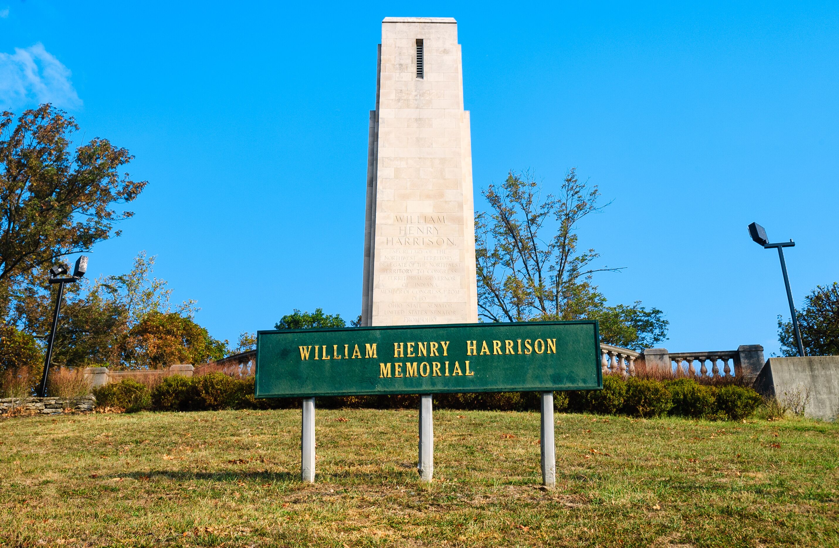 A memorial with a tall monument and a sign in front.