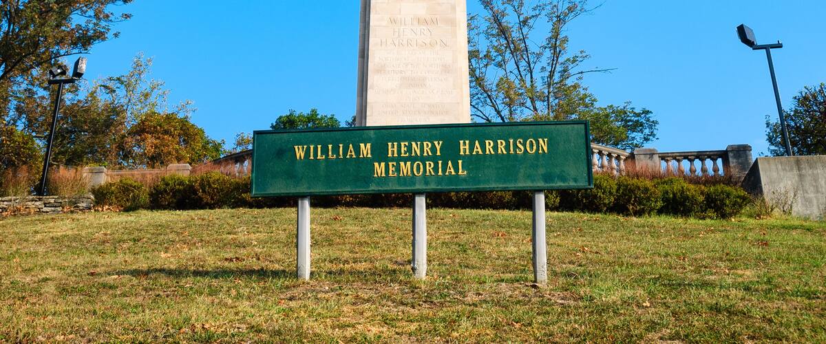 A memorial with a tall monument and a sign in front.