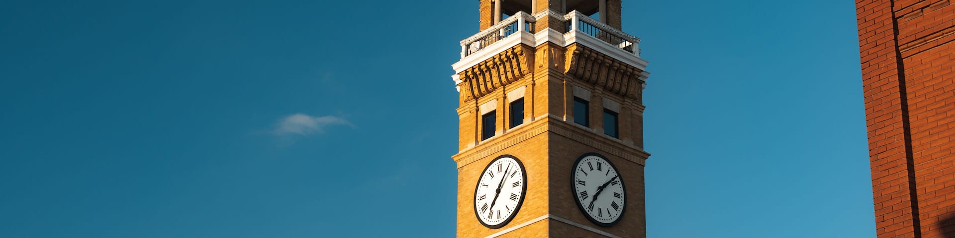 A clock tower with a balcony and a flag.