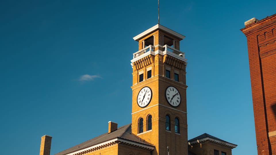 A clock tower with a balcony and a flag.