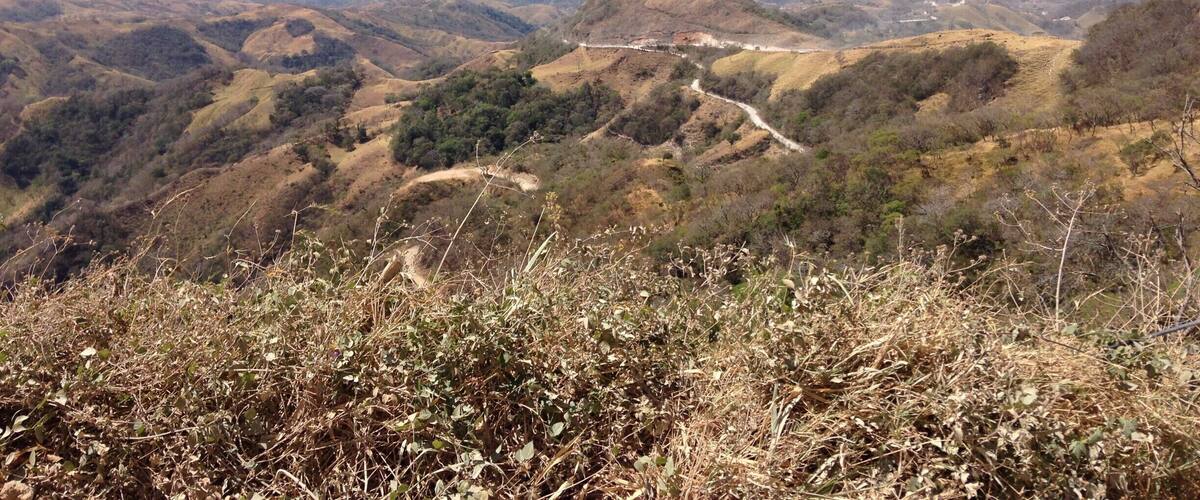 A mountainous landscape with winding roads and sparse vegetation.