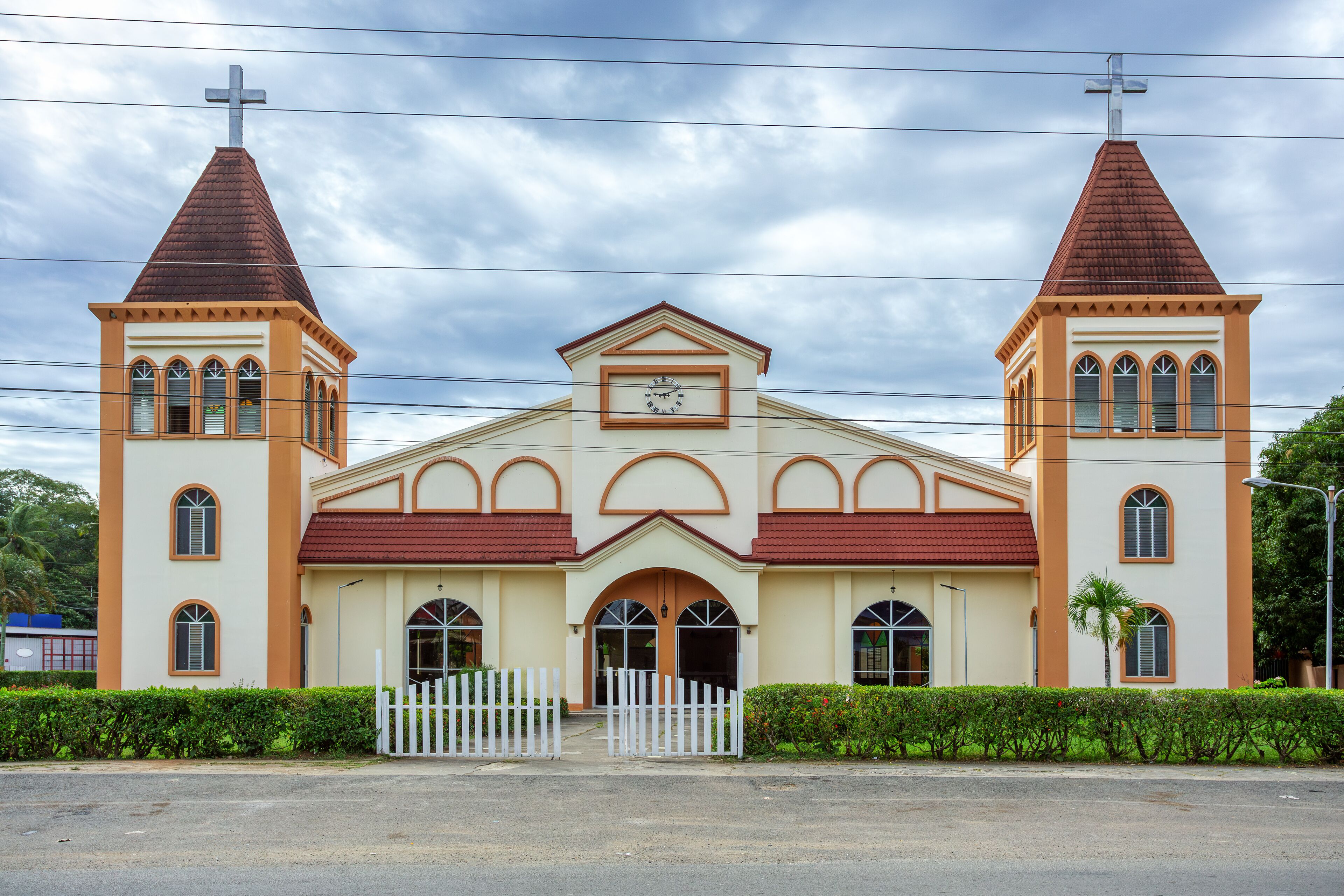 A church with a central arched entrance, two bell towers, and a clock above the entrance.