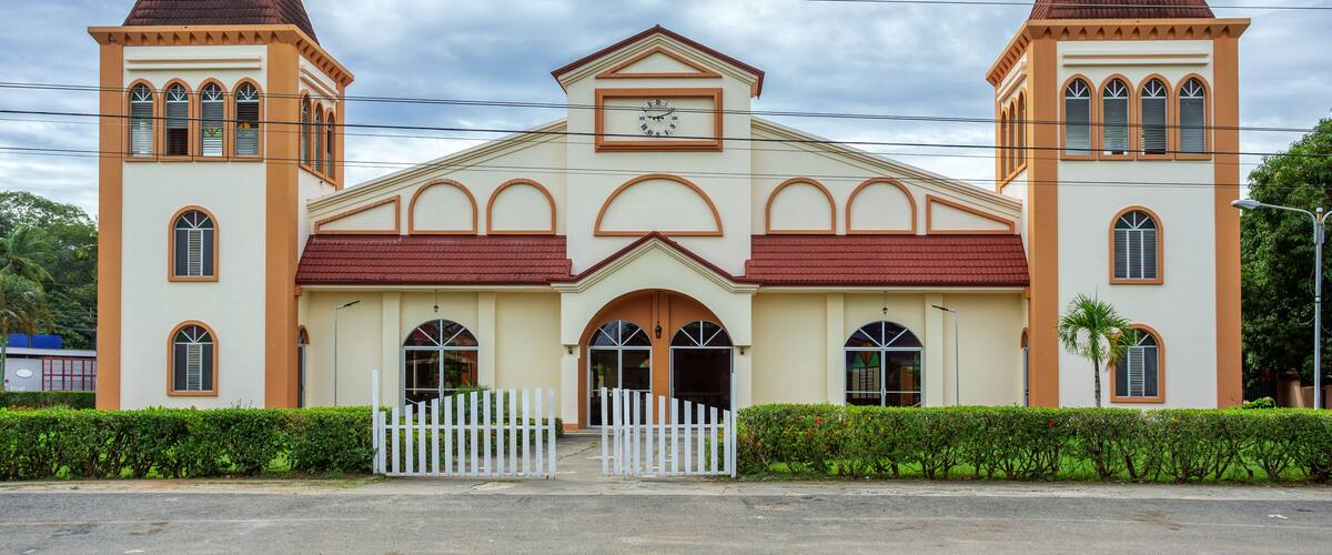 A church with a central arched entrance, two bell towers, and a clock above the entrance.