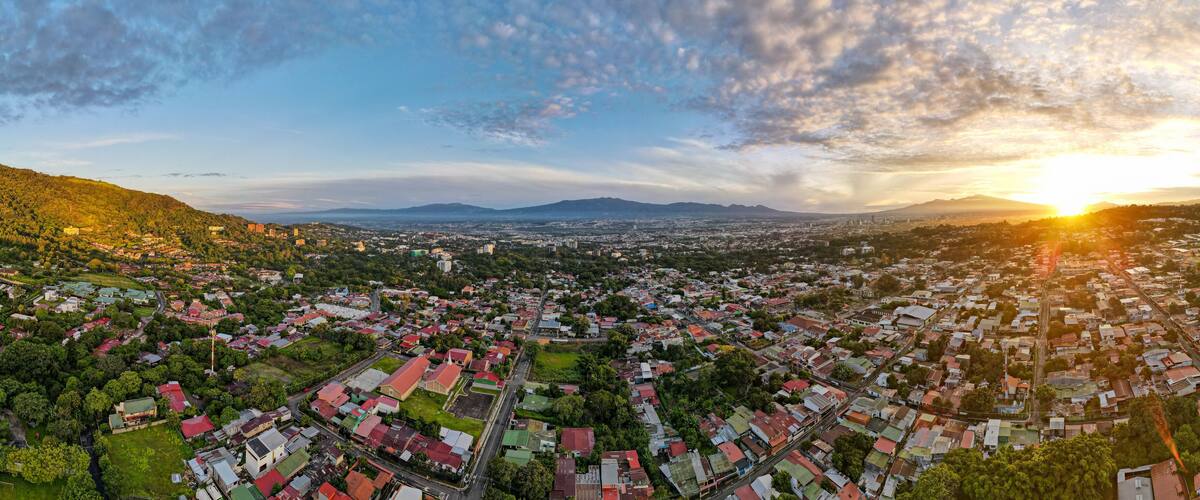 A panoramic view of a city with a mountainous backdrop and a sunset.
