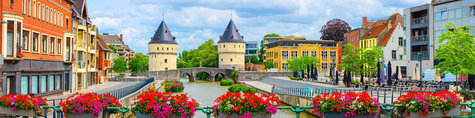 A historic town with a prominent bridge, colorful buildings, and flower-adorned railings.