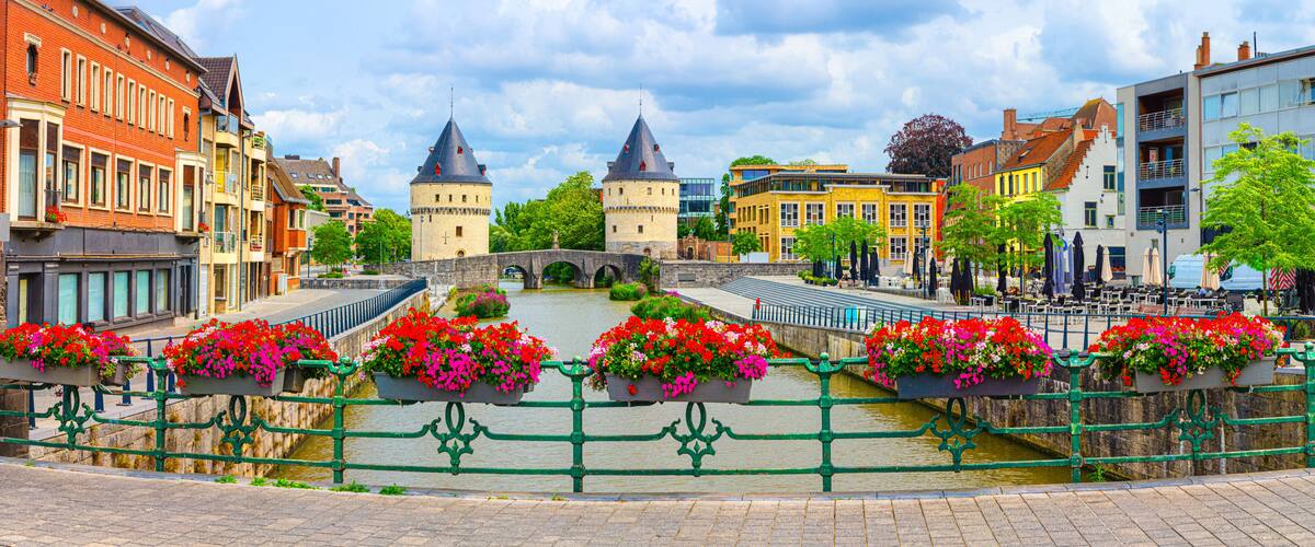 A historic town with a prominent bridge, colorful buildings, and flower-adorned railings.