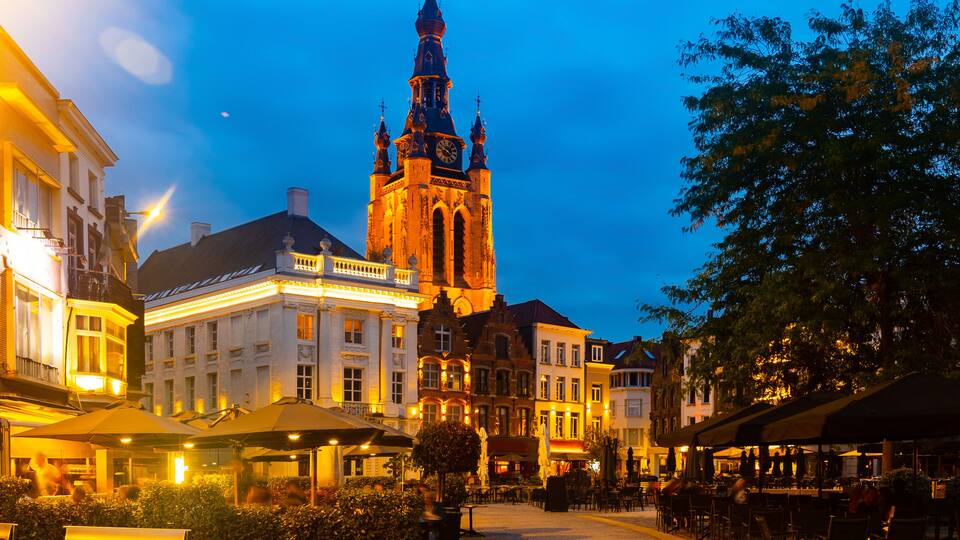 A historic town square with a prominent church tower, cobblestone streets, and traditional European architecture.