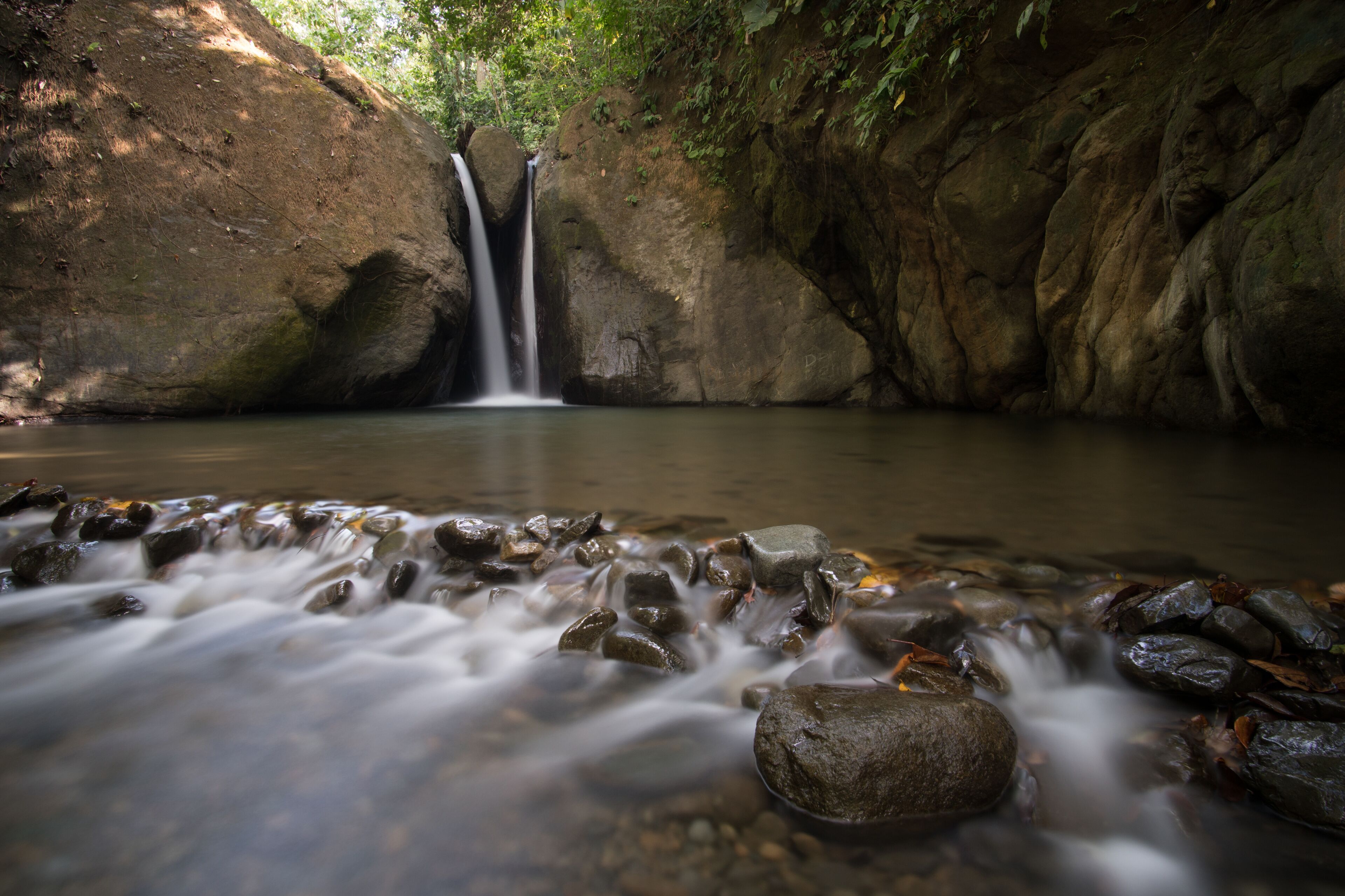A waterfall in a rocky, forested area.