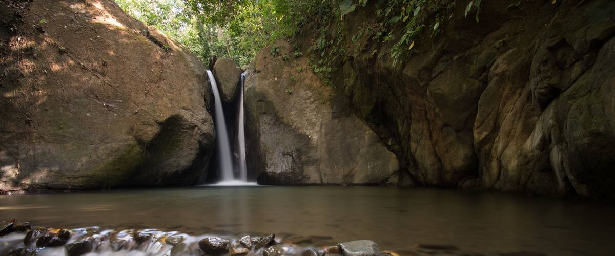 A waterfall in a rocky, forested area.