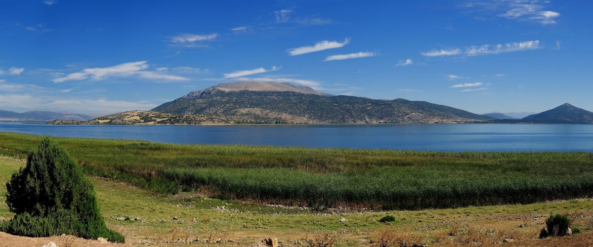 A lake with mountains in the background and a grassy foreground.