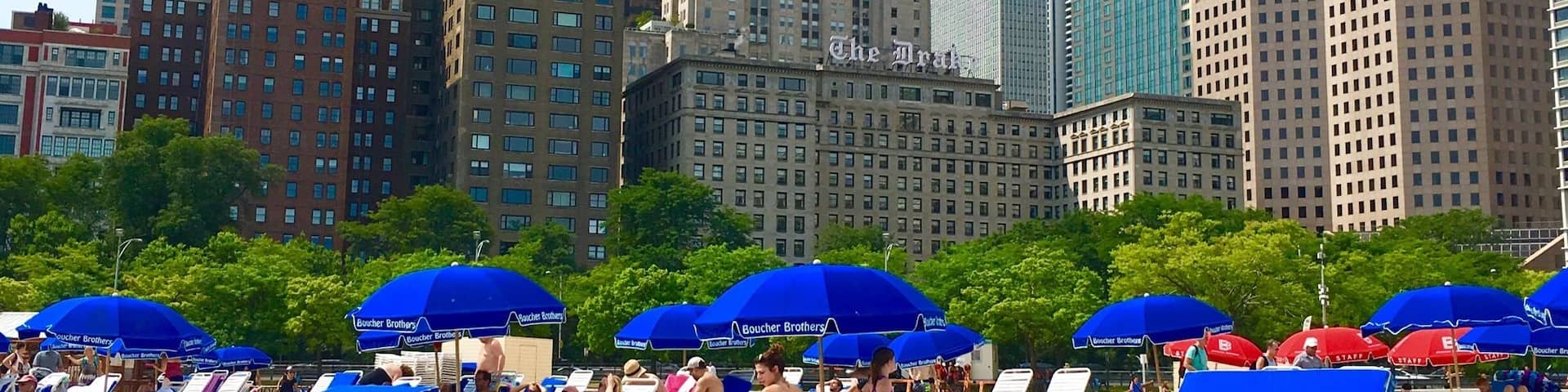 Un paisaje urbano con edificios altos y una zona de playa con sombrillas azules.