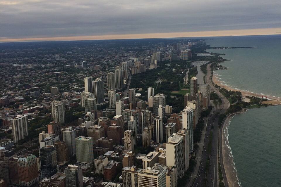 A coastal cityscape with high-rise buildings, a beach, and a river.