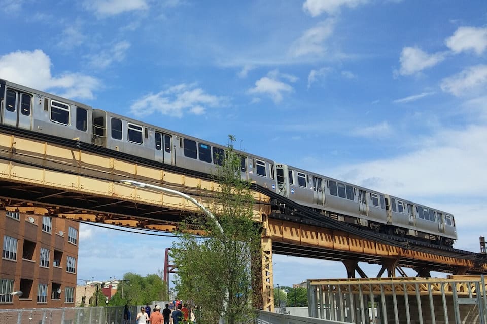 A train on an elevated track above a pedestrian walkway.