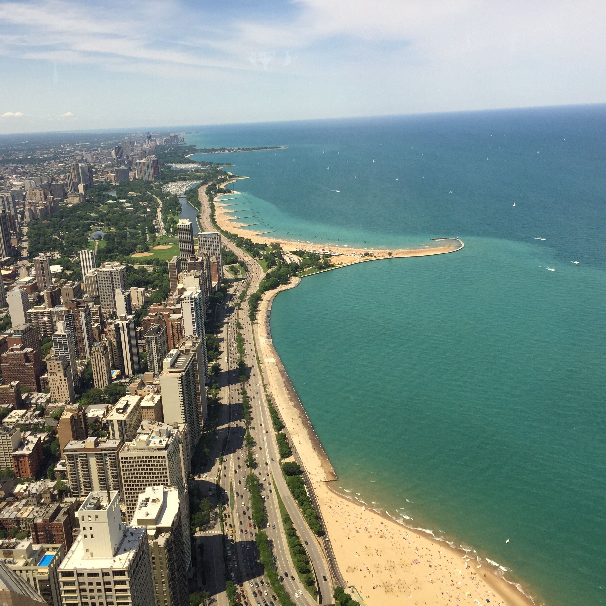 Un paisaje urbano costero con una playa extensa, edificios densos y un mar azul claro.