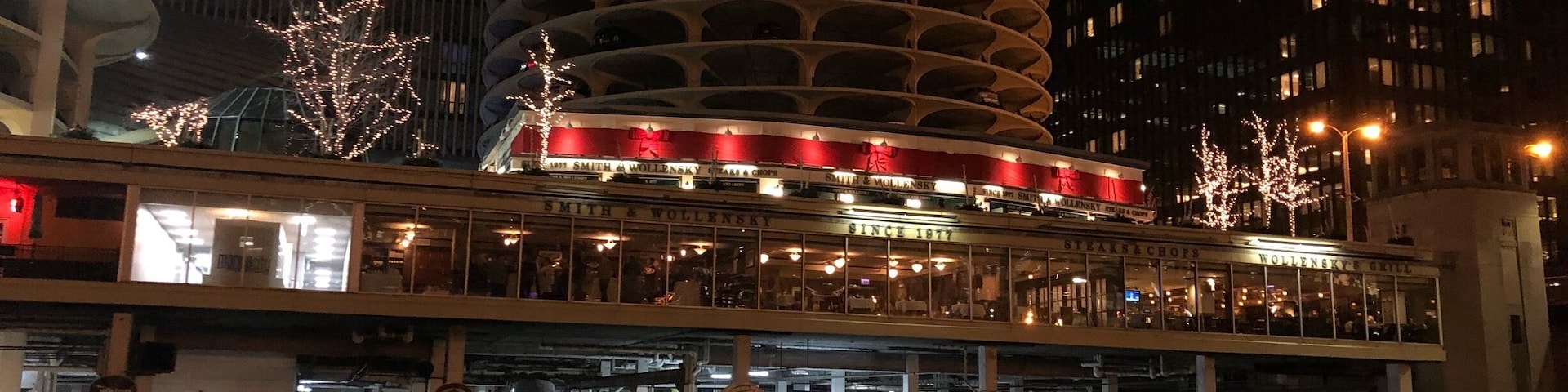 A waterfront restaurant with boats docked in the water, surrounded by tall buildings.