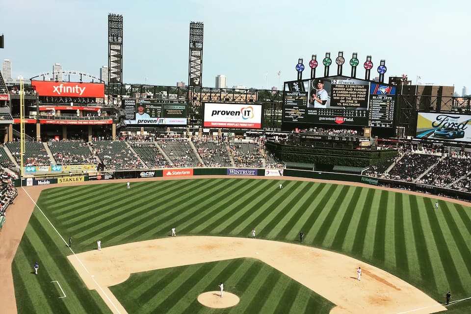 Um estádio de beisebol com publicidade, incluindo 'xfinity' e 'proven IT'.