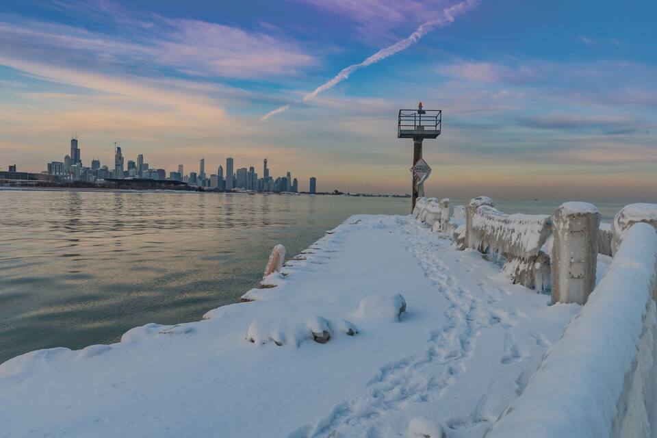 A snow-covered waterfront with a city skyline in the background.