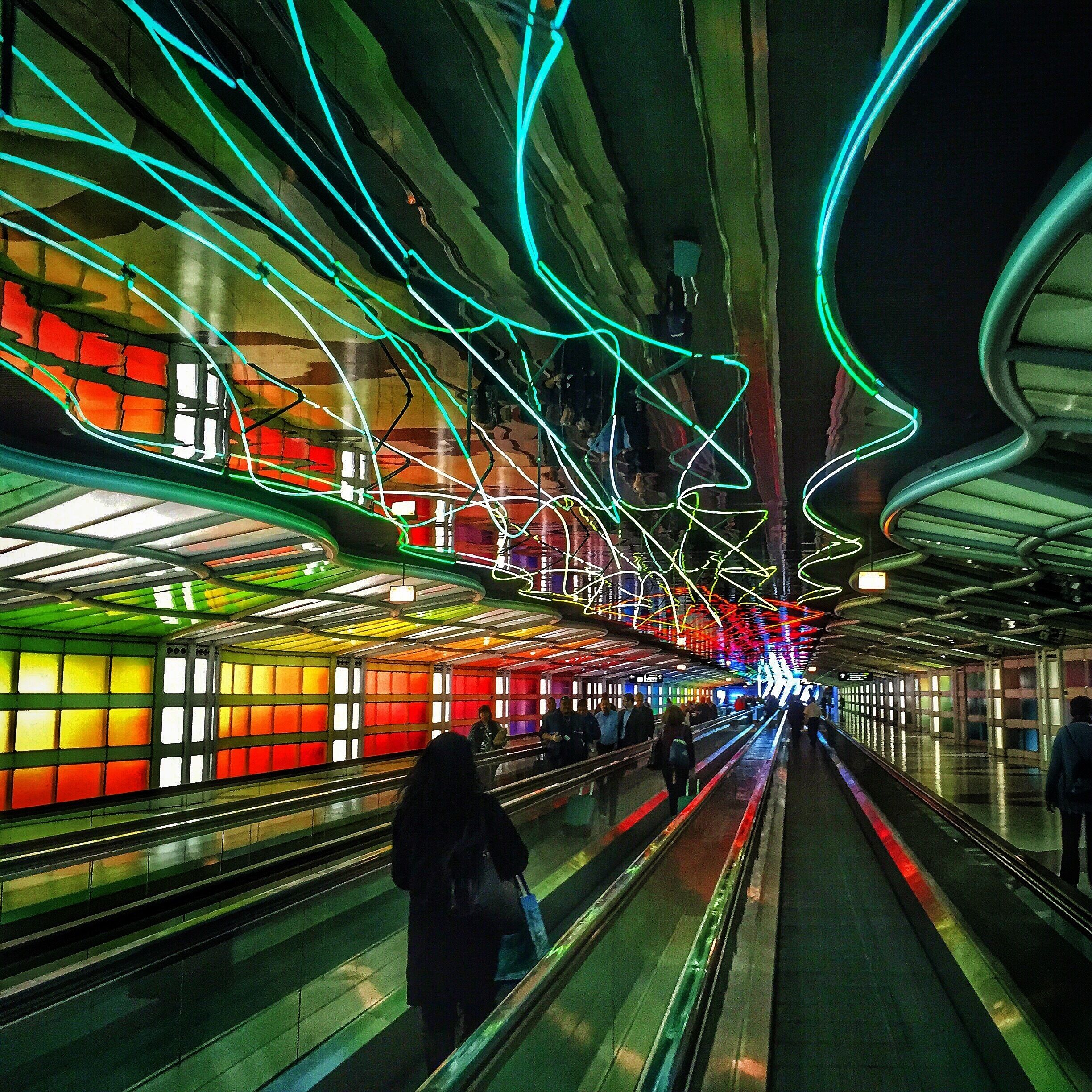 A subway station with colorful lights and a moving walkway.
