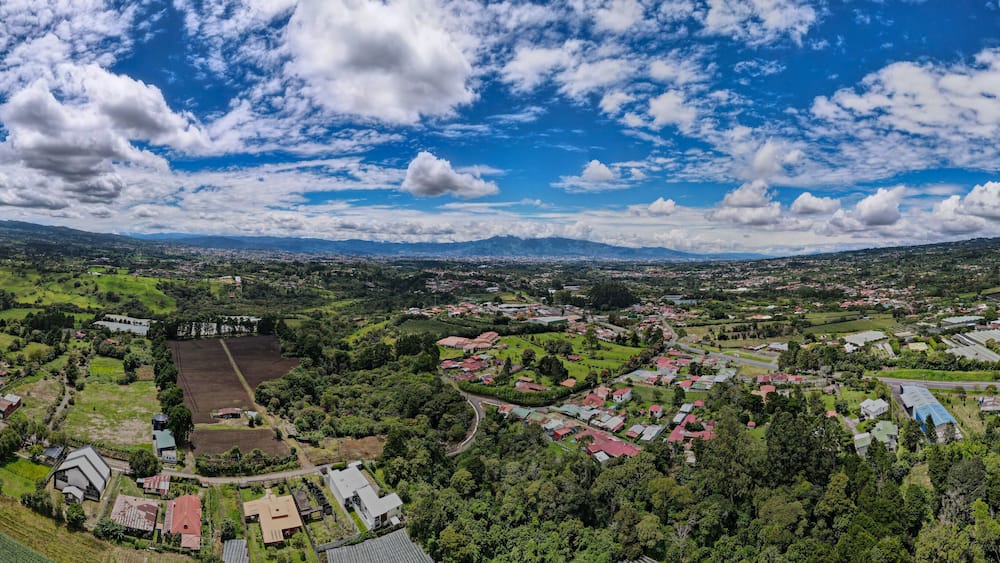 Une vue panoramique d’une ville entourée de montagnes et de verdure.