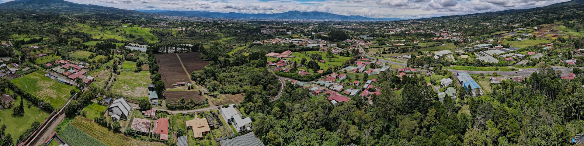 A panoramic view of a town surrounded by mountains and greenery.