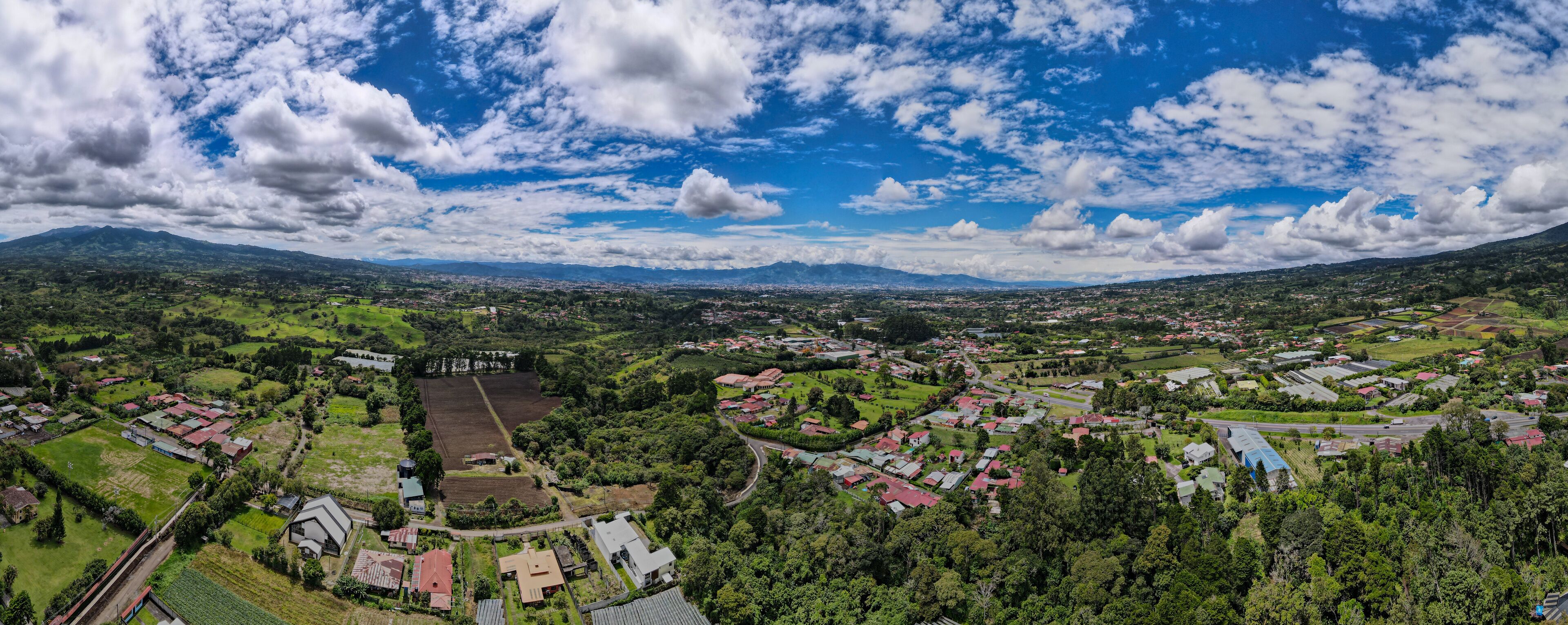 A panoramic view of a town surrounded by mountains and greenery.