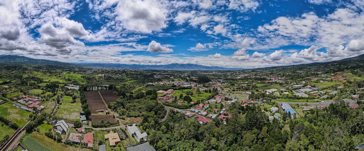 A panoramic view of a town surrounded by mountains and greenery.