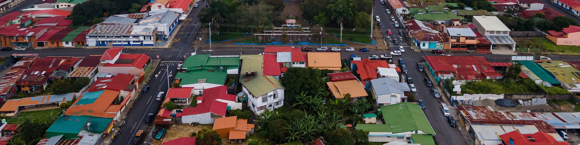 An aerial view of a city with a central plaza, surrounded by colorful buildings and a river in the background.