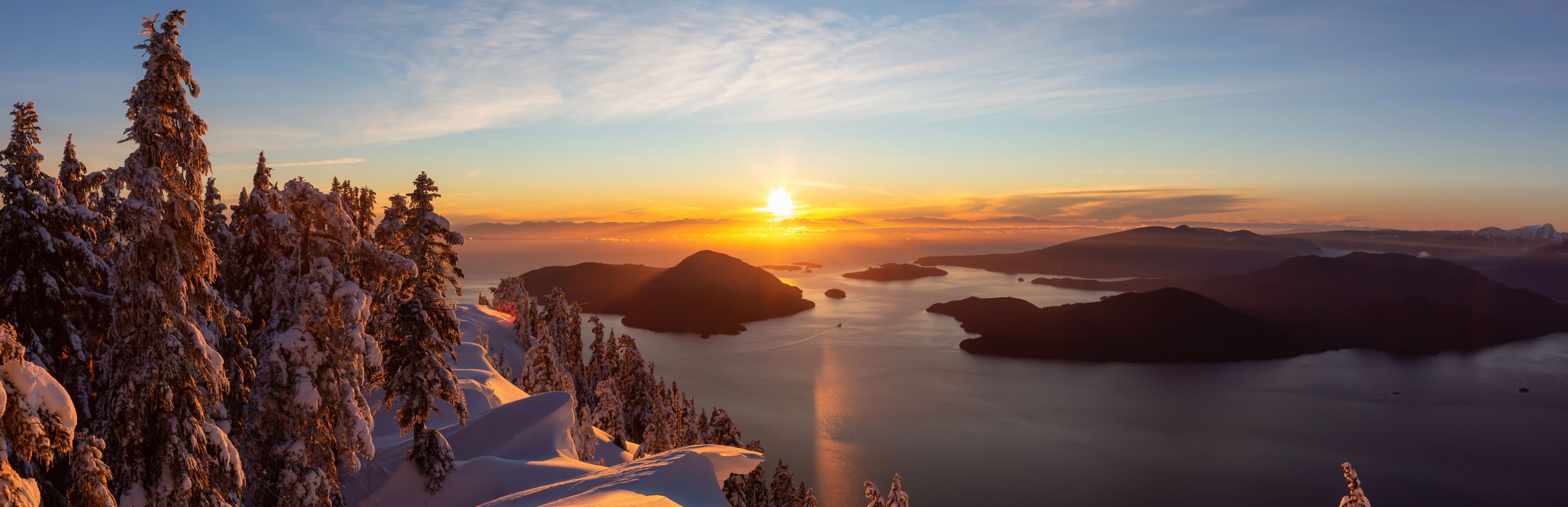 A snowy mountain landscape at sunset with a clear sky.