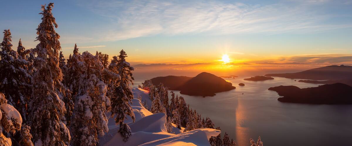 A snowy mountain landscape at sunset with a clear sky.
