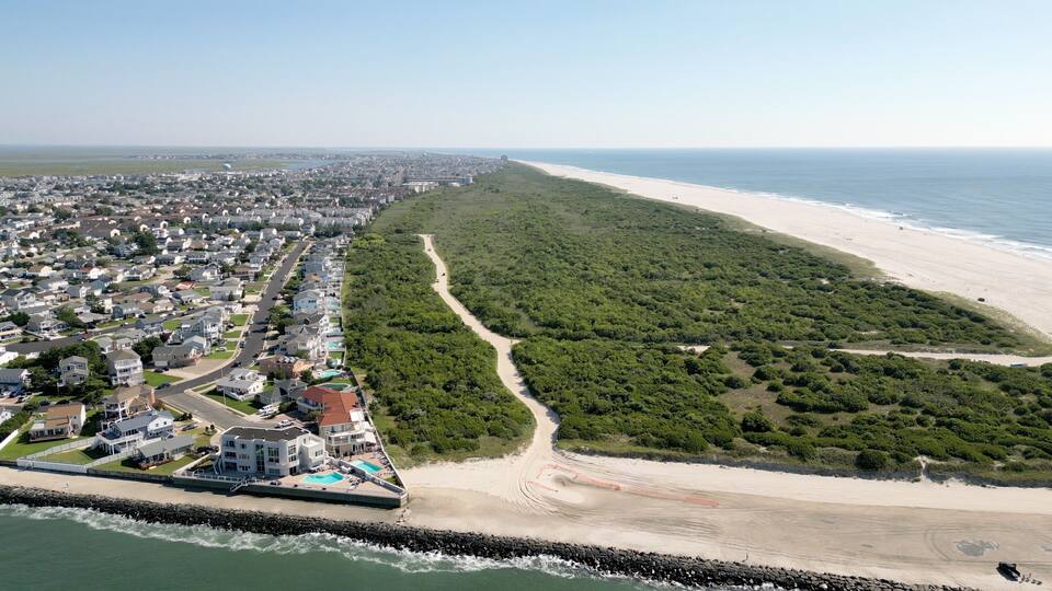 A coastal city with a long sandy beach, dense green vegetation, and residential areas.