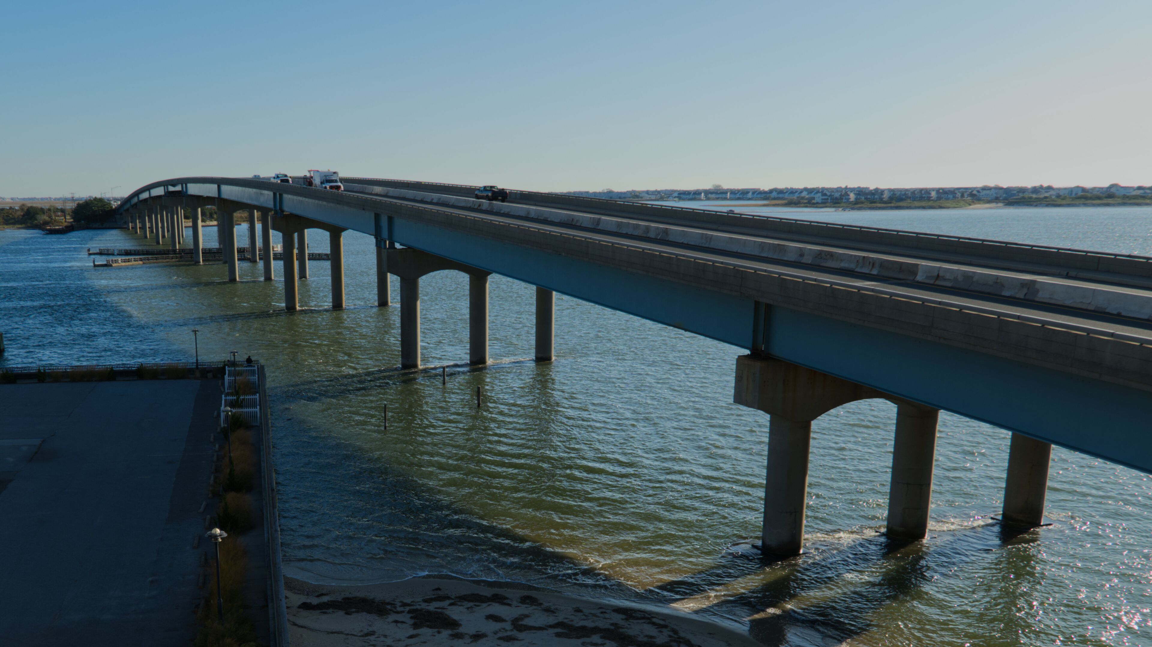 A bridge over a river with multiple piers, a clear sky, and distant buildings.