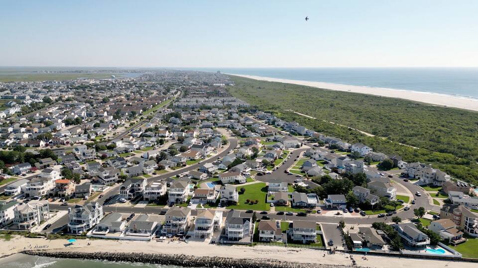 A coastal residential area with houses, roads, and a beach.