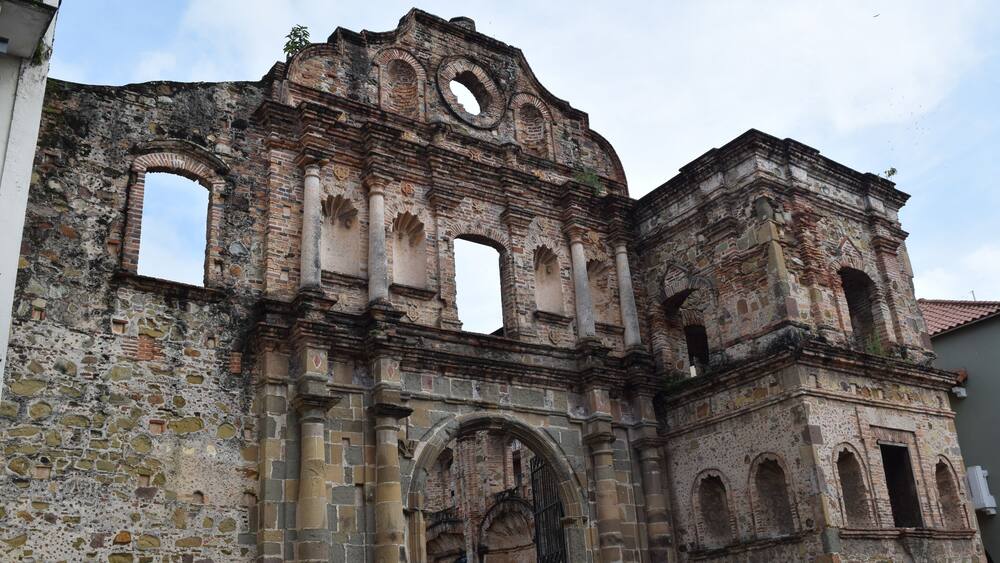 An old, partially ruined building with arched windows and a central doorway.