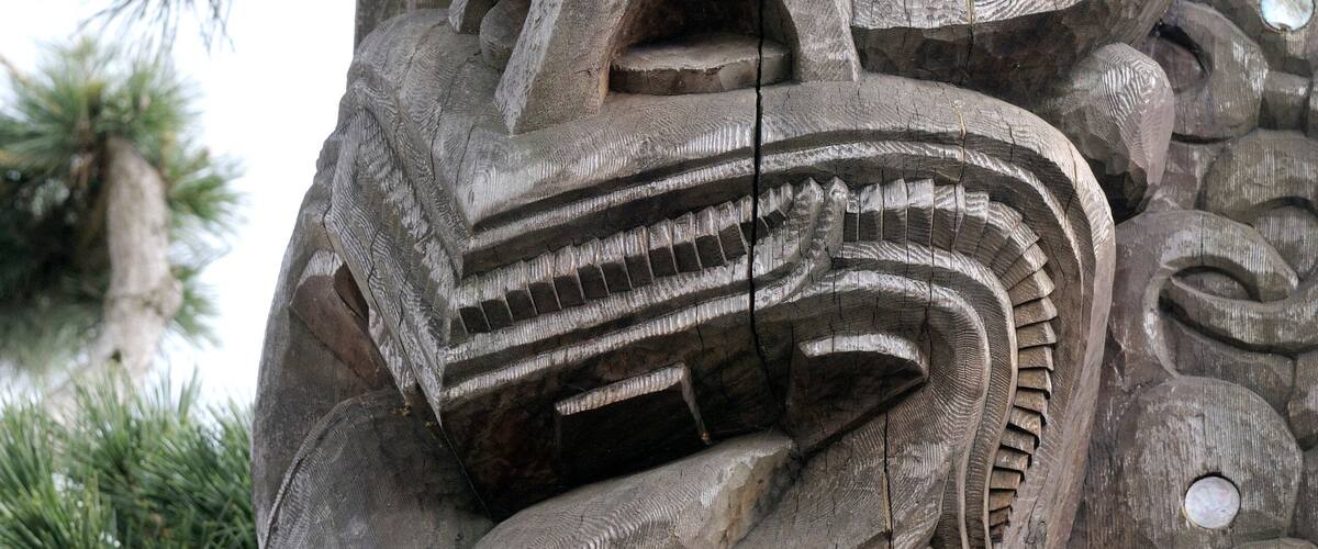 A detailed wooden sculpture with intricate carvings and a prominent face.